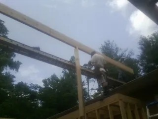 Carpenter setting a ridge beam over a new addition frame — Ice Dam Removal by Roofing Brothers in Logsden