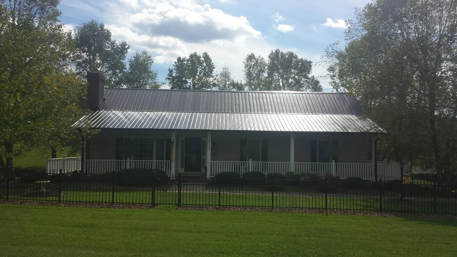 Gray metal roof on a brick ranch with a full width front porch — Gutter Guard Installation work by our crew in Logsden