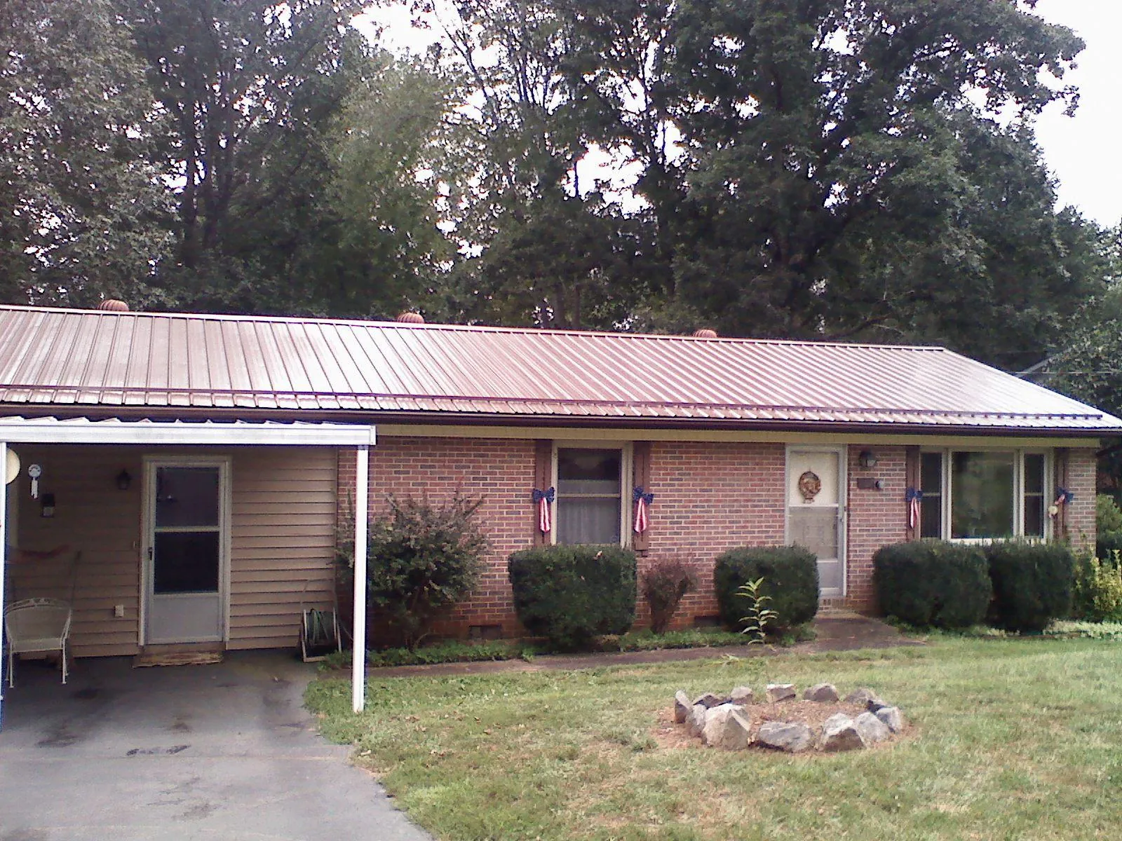 Bronze metal roof and carport on a brick ranch home — Roof Repair work by our crew in Logsden